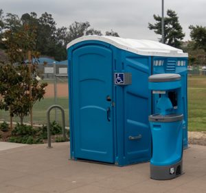 wheelchair accessible porta potty and hand washing station near a baseball field 